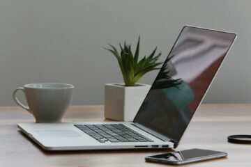 silver laptop and white cup on table